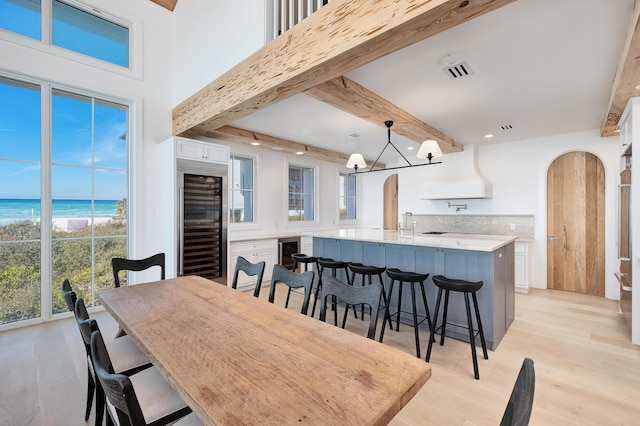 40 Jasmine Cir, Santa Rosa Beach, FL 32459 - dining room with beverage cooler, arched walkways, beam ceiling, light wood-type flooring, and recessed lighting