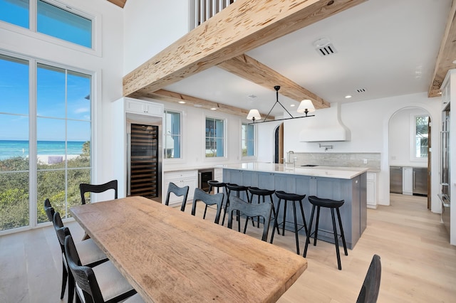 40 Jasmine Cir, Santa Rosa Beach, FL 32459 - dining area with wine cooler, beamed ceiling, view of water and beach, arched walkways, and light wood-type flooring
