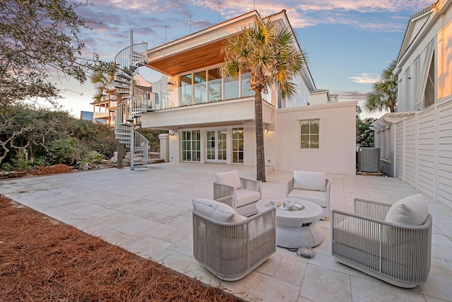 40 Jasmine Cir, Santa Rosa Beach, FL 32459 - back of house at dusk featuring stairway, a patio area, stucco siding, and an outdoor living space with a fire pit