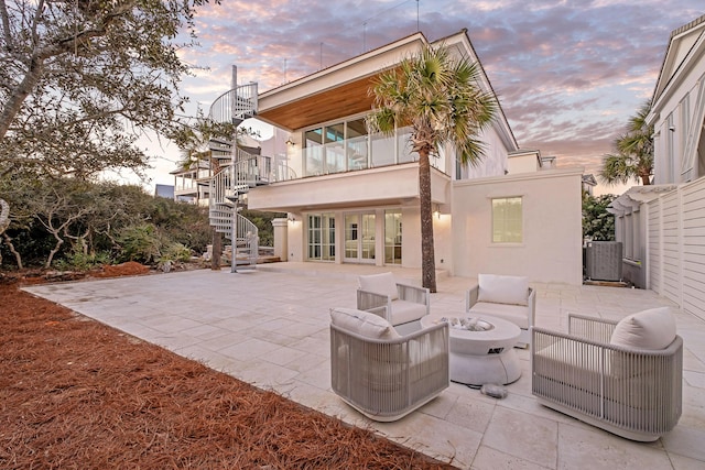 40 Jasmine Cir, Santa Rosa Beach, FL 32459 - back of house at dusk featuring stairs, a patio, stucco siding, french doors, and an outdoor living space with a fire pit