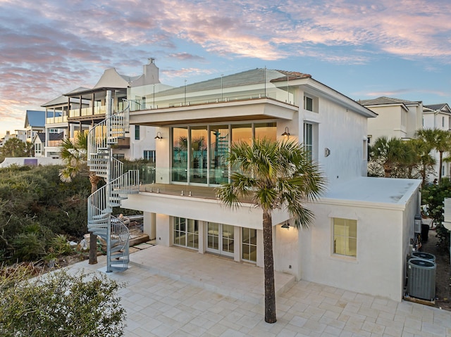 40 Jasmine Cir, Santa Rosa Beach, FL 32459 - back of house at dusk with stairs, central AC unit, stucco siding, and a patio area