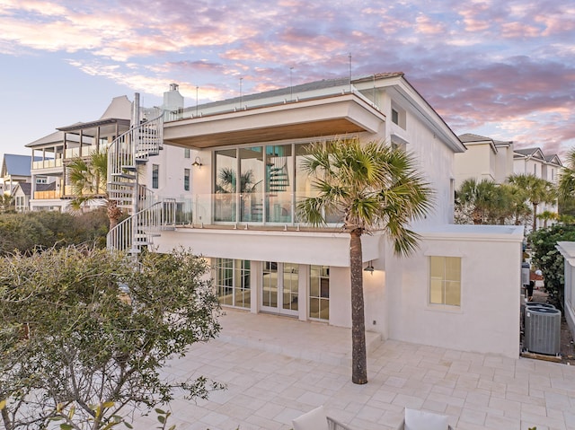 40 Jasmine Cir, Santa Rosa Beach, FL 32459 - back of house at dusk featuring central AC, stucco siding, stairway, and a patio