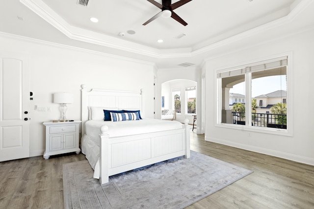 52 Tranquility Ln, Destin, FL 32541 - bedroom with a tray ceiling, arched walkways, wood finished floors, ornamental molding, and baseboards