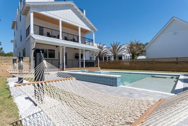 136 Lee Pl, Santa Rosa Beach, FL 32459 - rear view of property featuring a balcony, board and batten siding, a patio, and a pool with connected hot tub