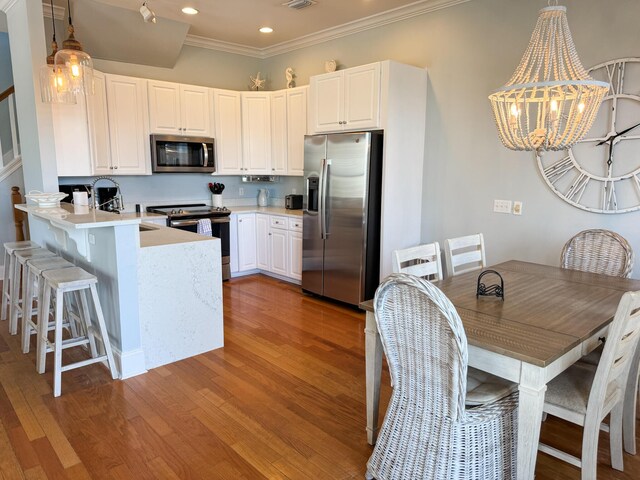 431 La Valencia Cir, Panama City Beach, FL 32413 - kitchen featuring stainless steel appliances, light wood-style floors, a peninsula, light countertops, and white cabinetry