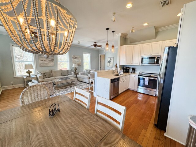 431 La Valencia Cir, Panama City Beach, FL 32413 - dining area featuring ornamental molding, light wood-style floors, a chandelier, baseboards, and ceiling fan