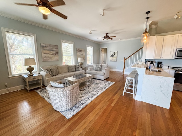 431 La Valencia Cir, Panama City Beach, FL 32413 - living area featuring a ceiling fan, stairs, light wood finished floors, crown molding, and baseboards