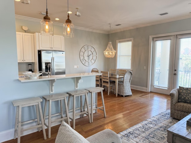 431 La Valencia Cir, Panama City Beach, FL 32413 - kitchen with stainless steel fridge with ice dispenser, light countertops, a kitchen bar, light wood-style flooring, and decorative light fixtures