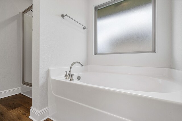 103 Ridgeway Cir, Crestview, FL 32536 - bathroom featuring a garden tub, wood finished floors, baseboards, and a shower with shower door