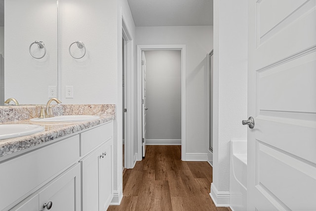 103 Ridgeway Cir, Crestview, FL 32536 - bathroom with wood finished floors, double vanity, a stall shower, baseboards, and a bathtub
