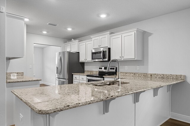 103 Ridgeway Cir, Crestview, FL 32536 - kitchen featuring appliances with stainless steel finishes, light stone countertops, a peninsula, a breakfast bar area, and recessed lighting