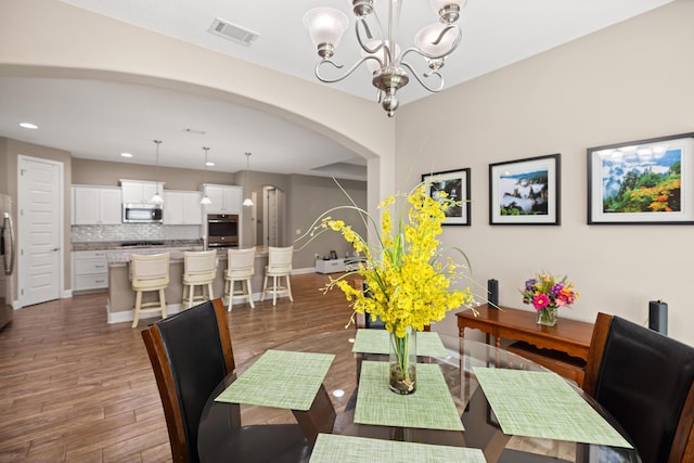 20 6th Ave, Shalimar, FL 32579 - dining space with a chandelier, arched walkways, recessed lighting, baseboards, and wood finished floors