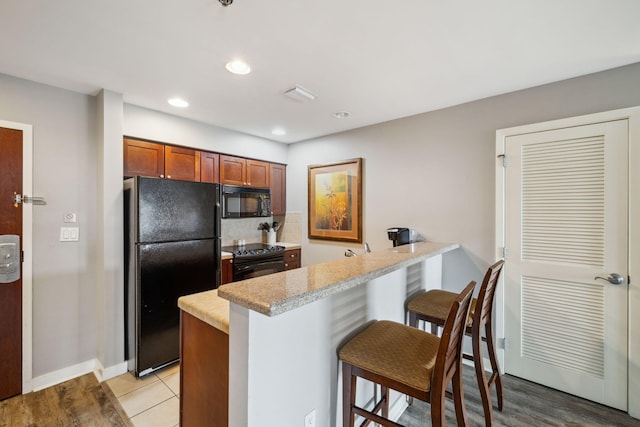5000 S Sandestin Blvd Unit 6407, Miramar Beach, FL 32550 - kitchen featuring black appliances, a peninsula, a kitchen breakfast bar, light countertops, and decorative backsplash