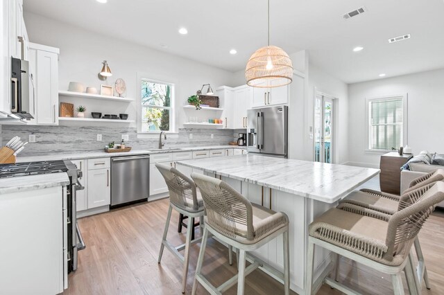 205 Redbud Ln, Inlet Beach, FL 32461 - kitchen featuring appliances with stainless steel finishes, open shelves, decorative backsplash, light wood-style flooring, and white cabinets