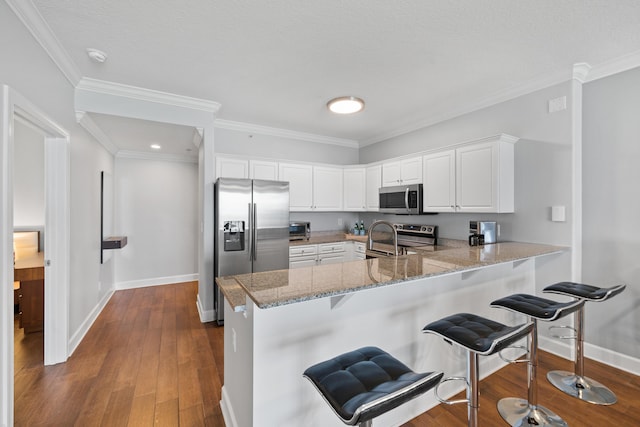 17545 Front Beach Rd Unit 1301, Panama City Beach, FL 32413 - kitchen featuring stainless steel appliances, baseboards, a peninsula, a breakfast bar, and ornamental molding