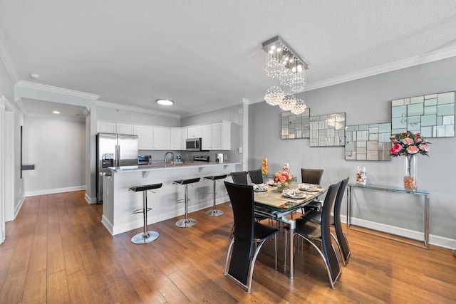 17545 Front Beach Rd Unit 1301, Panama City Beach, FL 32413 - dining room featuring a chandelier, baseboards, dark wood-type flooring, a textured ceiling, and crown molding