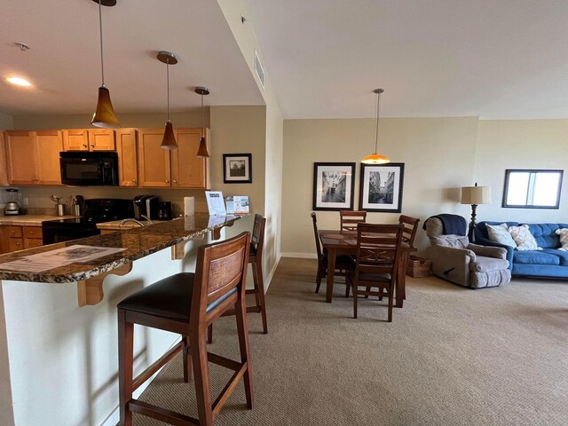 15100 Front Beach Rd Unit 831, Panama City Beach, FL 32413 - kitchen featuring black appliances, light carpet, a kitchen breakfast bar, decorative light fixtures, and a peninsula