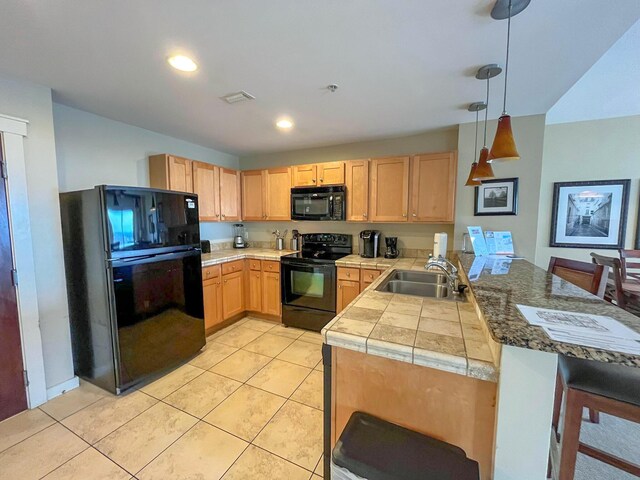 15100 Front Beach Rd Unit 831, Panama City Beach, FL 32413 - kitchen featuring black appliances, a peninsula, a sink, light brown cabinetry, and hanging light fixtures
