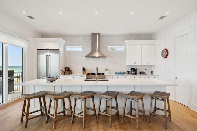 3464 Scenic Highway 98, Destin, FL 32541 - kitchen with wall chimney exhaust hood, high quality fridge, light wood finished floors, and white cabinets