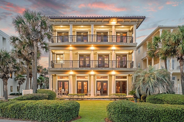 17 Saint Martin Cir, Miramar Beach, FL 32550 - back of house at dusk featuring french doors, a balcony, a lawn, and stucco siding