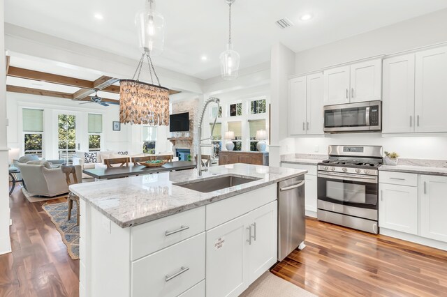 18 Eastern Lake Ct, Santa Rosa Beach, FL 32459 - kitchen featuring stainless steel appliances, open floor plan, a sink, a stone fireplace, and wood finished floors