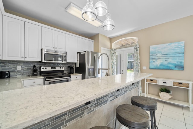 34 Opal Cv, Miramar Beach, FL 32550 - kitchen with stainless steel appliances, light stone counters, white cabinets, a breakfast bar area, and decorative backsplash