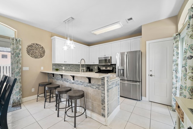 34 Opal Cv, Miramar Beach, FL 32550 - kitchen featuring stainless steel appliances, a peninsula, a breakfast bar area, backsplash, and light tile patterned flooring