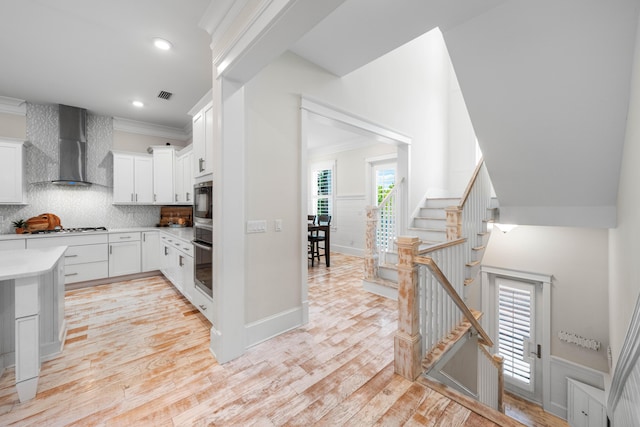 164 Clipper St, Inlet Beach, FL 32461 - kitchen featuring wall chimney range hood, light countertops, decorative backsplash, white cabinets, and light wood-style flooring