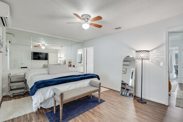 16 Court Dr, Destin, FL 32541 - bedroom with a wall mounted AC, wood finished floors, a textured ceiling, baseboards, and arched walkways