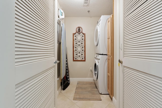 112 Seascape Dr Unit 1807, Miramar Beach, FL 32550 - laundry area featuring stacked washer and clothes dryer, light tile patterned flooring, and a textured ceiling