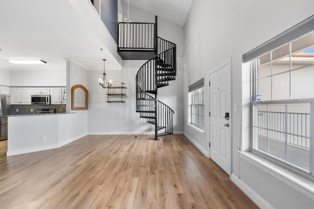 4507 Furling Ln Unit 302, Destin, FL 32541 - foyer featuring a chandelier, a towering ceiling, stairway, and light wood-style flooring