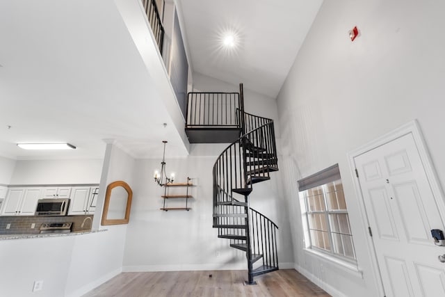 4507 Furling Ln Unit 302, Destin, FL 32541 - stairway featuring high vaulted ceiling, wood finished floors, a chandelier, and baseboards