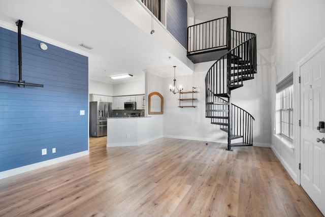 4507 Furling Ln Unit 302, Destin, FL 32541 - unfurnished living room with a chandelier, stairway, light wood finished floors, a high ceiling, and baseboards