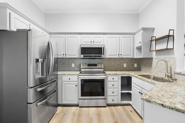 4507 Furling Ln Unit 302, Destin, FL 32541 - kitchen featuring appliances with stainless steel finishes, open shelves, a sink, ornamental molding, and light wood finished floors