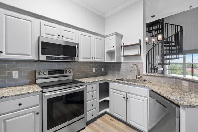 4507 Furling Ln Unit 302, Destin, FL 32541 - kitchen with appliances with stainless steel finishes, a sink, ornamental molding, open shelves, and white cabinetry