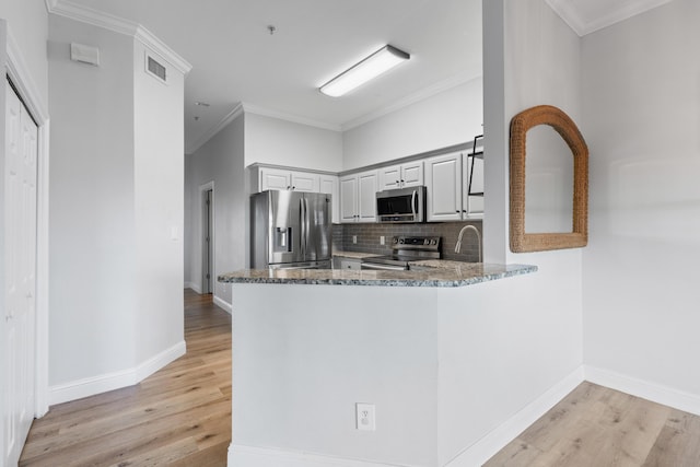 4507 Furling Ln Unit 302, Destin, FL 32541 - kitchen with stainless steel appliances, light wood-style flooring, dark stone counters, tasteful backsplash, and a peninsula