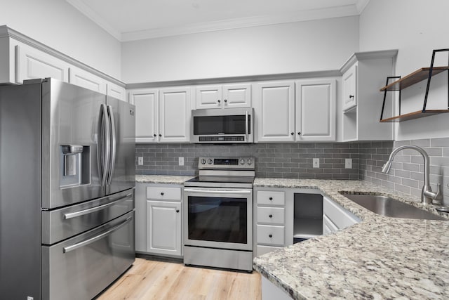 4507 Furling Ln Unit 302, Destin, FL 32541 - kitchen featuring appliances with stainless steel finishes, a sink, ornamental molding, open shelves, and light stone counters