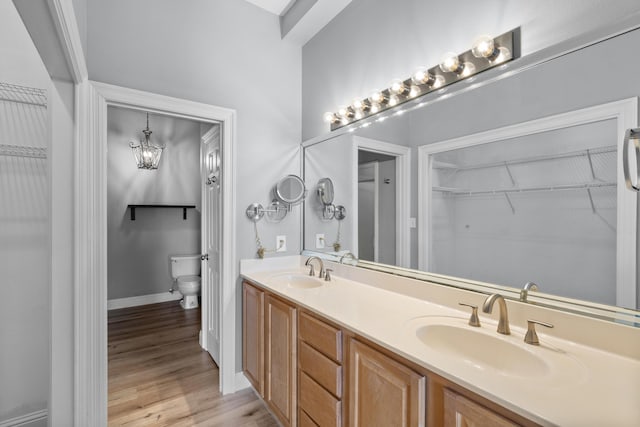 4507 Furling Ln Unit 302, Destin, FL 32541 - bathroom featuring toilet, double vanity, wood finished floors, a spacious closet, and baseboards