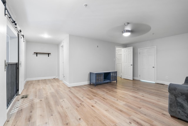 4507 Furling Ln Unit 302, Destin, FL 32541 - living area with a barn door, ceiling fan, light wood-style floors, and baseboards