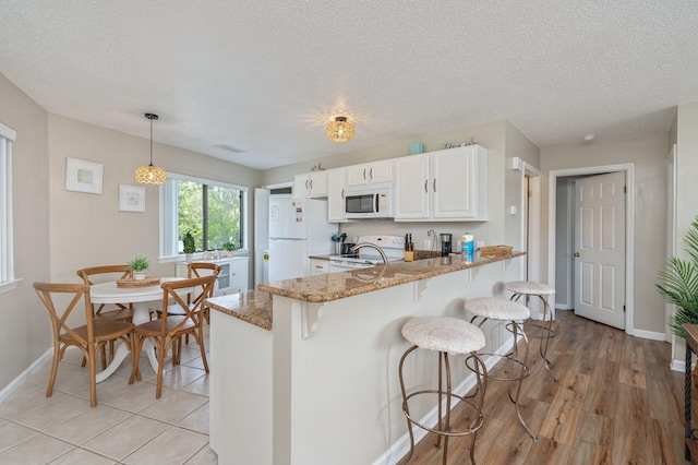 285 Payne St Unit 23B, Miramar Beach, FL 32550 - kitchen with white appliances, a kitchen bar, light stone counters, a peninsula, and baseboards
