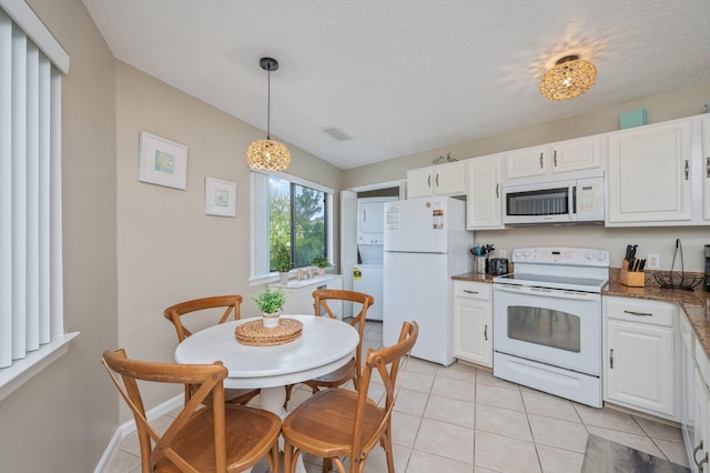 285 Payne St Unit 23B, Miramar Beach, FL 32550 - kitchen featuring white appliances, white cabinets, light tile patterned flooring, decorative light fixtures, and dark stone countertops