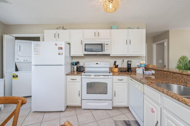 285 Payne St Unit 23B, Miramar Beach, FL 32550 - kitchen featuring white appliances, stacked washer and clothes dryer, white cabinetry, light tile patterned floors, and a textured ceiling