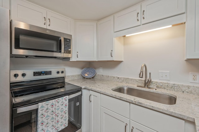 308 Miracle Strip Pkwy Unit 16B, Fort Walton Beach, FL 32548 - kitchen with appliances with stainless steel finishes, a sink, white cabinets, and light stone counters
