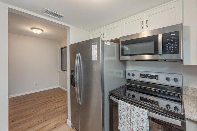 308 Miracle Strip Pkwy Unit 16B, Fort Walton Beach, FL 32548 - kitchen with stainless steel appliances, light wood finished floors, white cabinetry, baseboards, and light stone counters