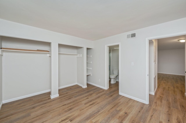 308 Miracle Strip Pkwy Unit 16B, Fort Walton Beach, FL 32548 - unfurnished bedroom featuring multiple closets, wood finished floors, baseboards, and ensuite bathroom