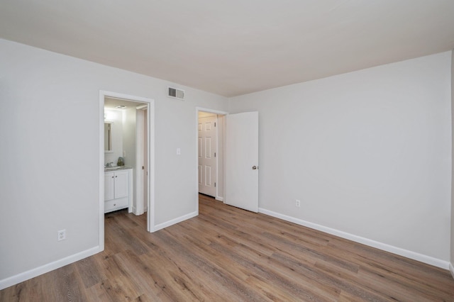 308 Miracle Strip Pkwy Unit 16B, Fort Walton Beach, FL 32548 - unfurnished bedroom featuring wood finished floors, baseboards, and ensuite bathroom