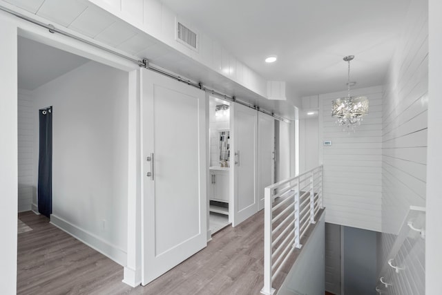 4 SW Miracle Strip Pkwy Unit 23, Fort Walton Beach, FL 32548 - corridor featuring a barn door, light wood-type flooring, a chandelier, recessed lighting, and an upstairs landing