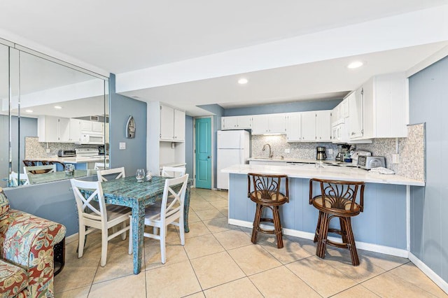 667 Nautilus Ct Unit 302, Fort Walton Beach, FL 32548 - kitchen with white appliances, decorative backsplash, a sink, a peninsula, and white cabinetry