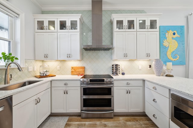 300 Cassine Garden Cir, Santa Rosa Beach, FL 32459 - kitchen featuring stainless steel appliances, wall chimney exhaust hood, crown molding, white cabinets, and light wood finished floors