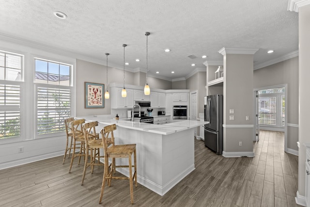 72 Tranquility Ln, Destin, FL 32541 - kitchen featuring appliances with stainless steel finishes, a peninsula, wood finished floors, a breakfast bar, and a textured ceiling